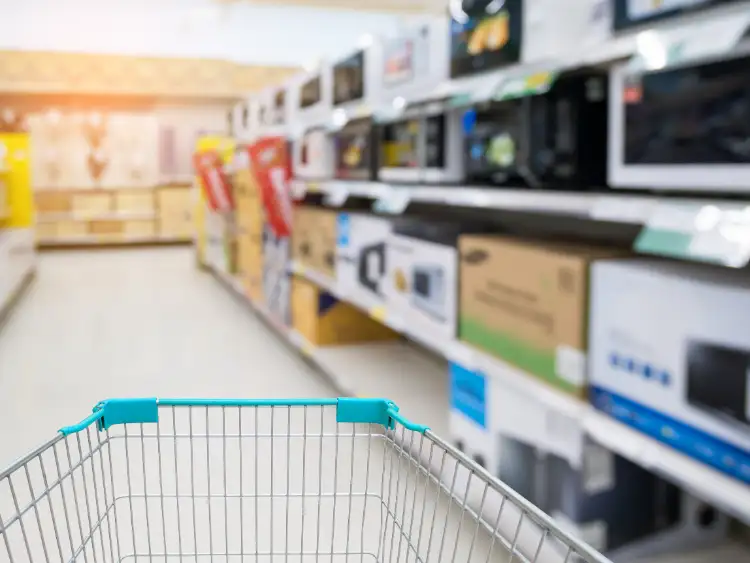 Ein Einkaufswagen steht mitten im Supermarkt neben einem Regal voller Hardware.